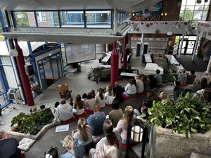 Elevar og lærarar sit samla i Fuglaberget på Leite og ser på ein video på storskjerm